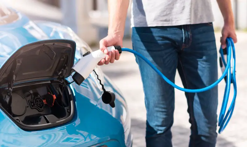 man charging electric vehicle